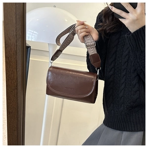 Detail van bruine retro crossbodytas met brede jacquardriem en modieuze belettering