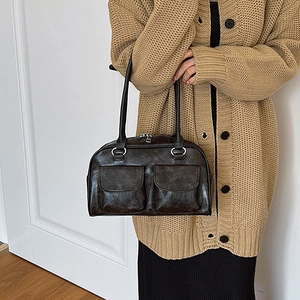 Retro dark brown leather shoulder bag with dual front pockets worn over knit cardigan