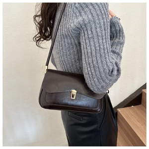 Side view of a vintage chocolate brown underarm bag with gold buckle and leather texture