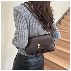 Deep brown leather underarm bag with gold clasp shown on model for a retro casual style