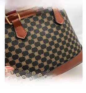 Detail view of vintage monogram floral pattern and gold metal rings on leather handbag