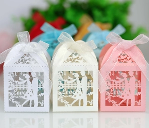 Detail of laser-cut wedding favor boxes with couple motif and soft organza ribbons