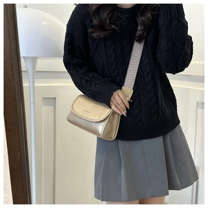 Detail van gouden crossbody tas met brede jacquard band op een vrouwelijk model getoond