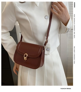 Détail d'un sac bandoulière en cuir marron vintage avec boucle dorée porté avec un blazer