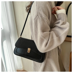 French vintage black crossbody bag with gold buckle shown on a knit sweater