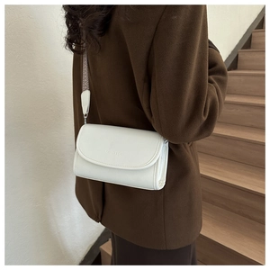 Detail van witte crossbodytas met geometrische geweven riem gedragen door een model