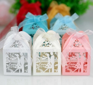 Detail of laser-cut wedding favor boxes with bride and groom silhouette and ribbon
