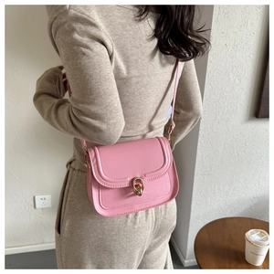 Gros plan sur un sac à bandoulière en cuir rose mat avec boucle en métal doré