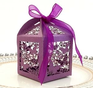 Macro shot of purple laser-cut wedding favor box with butterfly pattern and ribbon