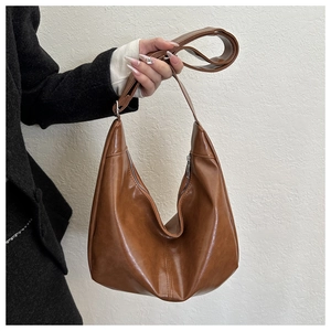 Detail of a brown leather hobo bag featuring fine stitching and an adjustable shoulder strap