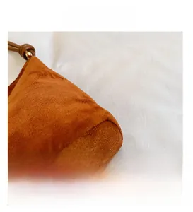 Gros plan d'un sac cabas en daim camel avec cordon en cuir marron et détail de perle dorée