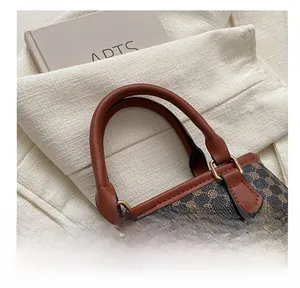 Detail of vintage tote bag showing printed pattern and golden metal hardware handle joint