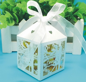 Close-up of laser-cut wedding candy box with heart pattern and white ribbon bow