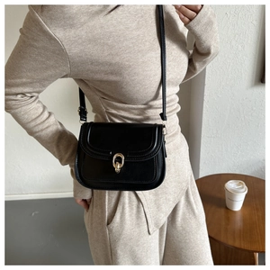 Détail du sac à bandoulière noir avec fermoir rotatif en forme de fer à cheval doré