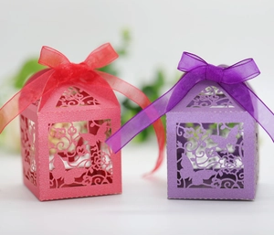 Detail of laser-cut hollow candy boxes with floral butterfly patterns and organza ribbons