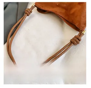 Détail du cabas en daim marron avec bandoulière nouée et détails de broderie fins