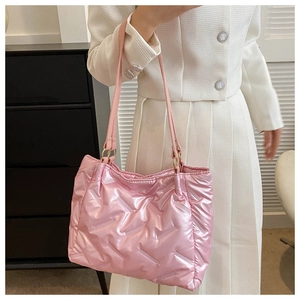 Gros plan sur le sac fourre-tout matelassé rose métallisé porté à l'épaule par un mannequin