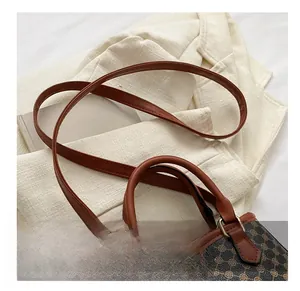 Close-up of vintage patterned crossbody bag with brown leather straps on a beige blazer