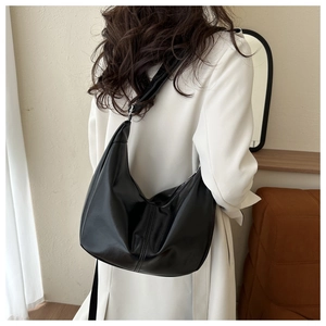 Detail of minimalist black hobo shoulder bag styled with a white blazer for daily commute