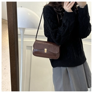 Close-up of vintage brown leather underarm bag featuring a metallic gold buckle closure