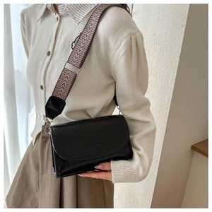 Detail van zwarte crossbody tas met brede geweven riem en FASHION BAGS reliëflogo
