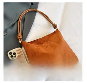 Détail du sac cabas en daim marron avec texte embossé et smartphone pour comparer la taille