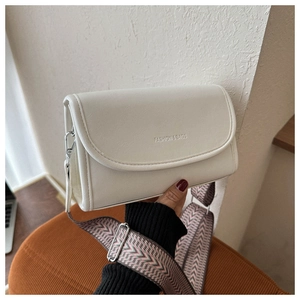Detail van witte crossbodytas met brede geometrische riem en metalen gesp op zijkant