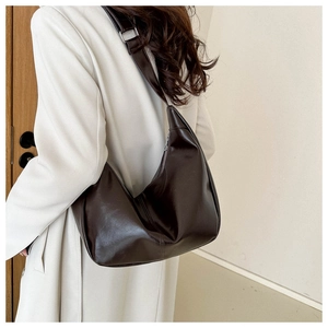 Detail of dark brown hobo shoulder bag with smooth leather texture and metal buckle