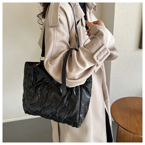Détail du sac cabas matelassé noir brillant avec de fines bandoulières en cuir