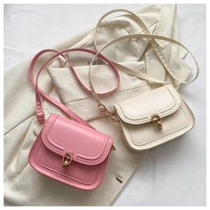 Vue détaillée de sacs de selle rose et beige avec fermoirs dorés sur un blazer texturé