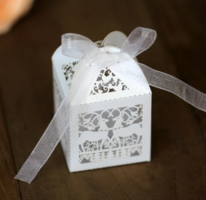 Close-up of white laser-cut reindeer gift box with ribbon on dark wood background