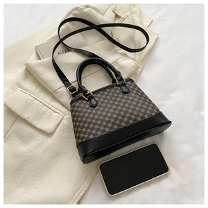 Top view of a small printed crossbody bag on a tweed jacket with a phone for size reference