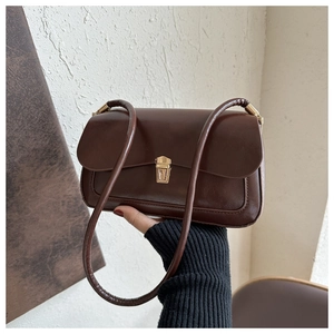 Close-up of a vintage brown leather underarm bag with elegant gold metal buckle closure