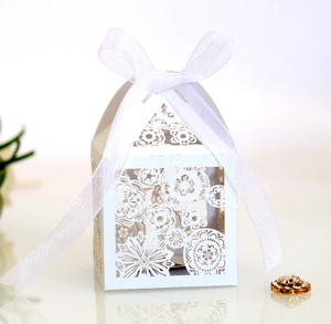Macro detail of laser-cut floral pattern on white wedding candy box with organza ribbon