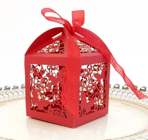 Detailed close-up of a red laser-cut wedding favor box with butterfly pattern and ribbon