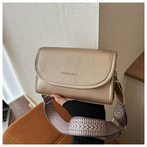 Detail van de champagnegouden crossbodytas met kiezeltextuur en brede riem met patroon