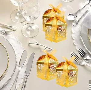 Detail of laser-cut gold wedding favor box featuring a yellow ribbon bow and hollow patterns