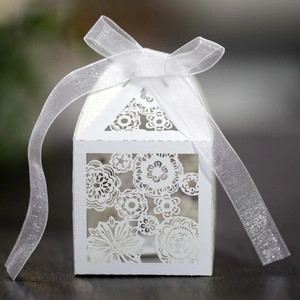 Detailed close-up of intricate laser-cut floral patterns on a white wedding favor box