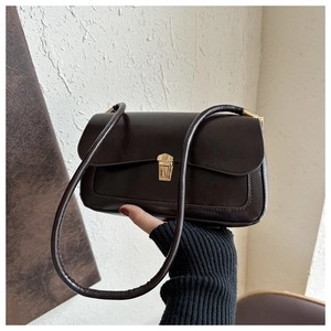 Detail of vintage chocolate brown faux leather crossbody bag with gold buckle hardware
