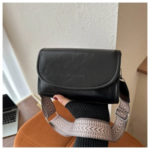 Detail van zwarte crossbodytas met een brede kleurrijke etnisch geweven schouderband