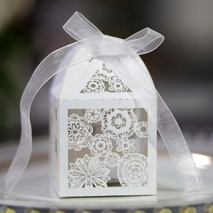 Detailed laser-cut floral pattern on white wedding candy box with organza ribbon