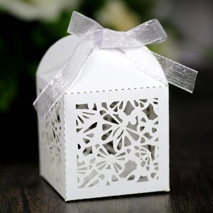 Detail of white laser-cut gift box with butterfly patterns and a silver satin ribbon bow