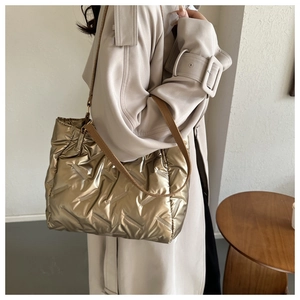 Détail du sac fourre-tout matelassé doré métallisé avec texture ondulée et anses en cuir