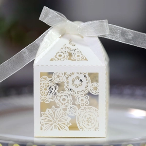 Close-up of laser-cut floral wedding favor box with white organza ribbon bow