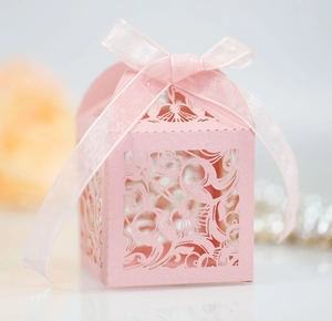 Vue détaillée de la boîte de dragées rose découpée au laser avec ruban satiné et motifs fleurs