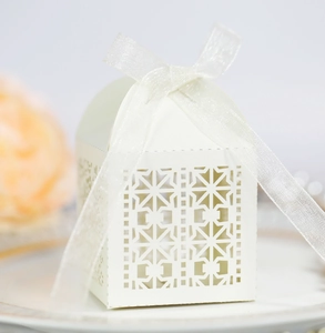 Macro view of ivory laser-cut candy box with geometric patterns and sheer organza ribbon