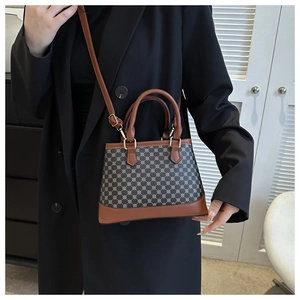 Chic brown geometric print crossbody bag styled on shoulder in a cozy home setting