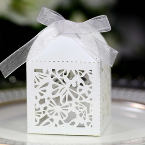 Detail of laser-cut butterfly gift box with elegant ribbon bow on a white plate