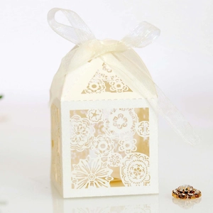 Macro detail of laser-cut floral ivory candy box with cream organza ribbon bow