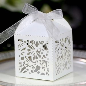 Detail of laser-cut butterfly floral patterns on white wedding candy box with ribbon